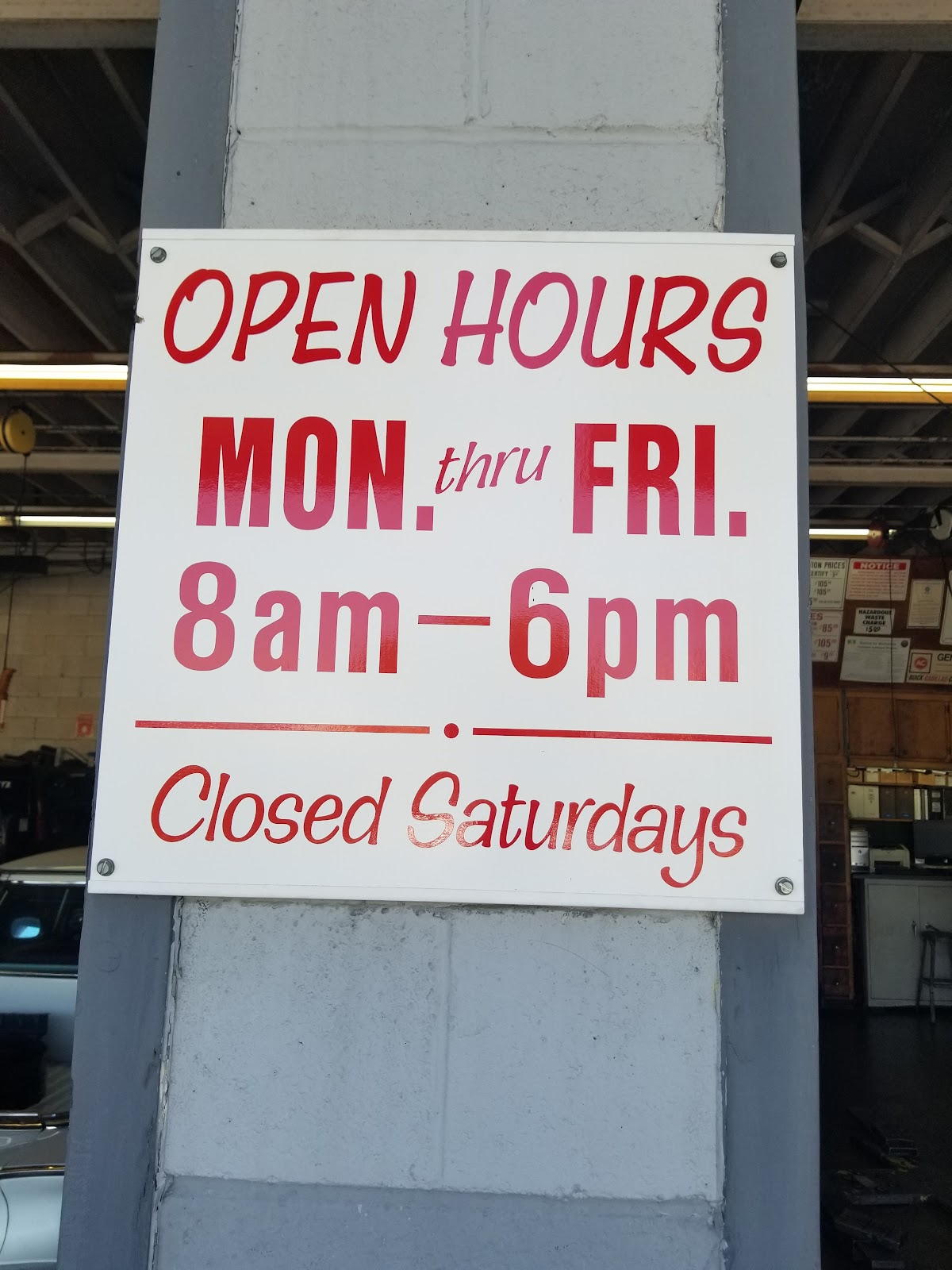 The hand painted opening hours sign inside the shop, Monday through Friday 8am to 6pm, closed Saturdays